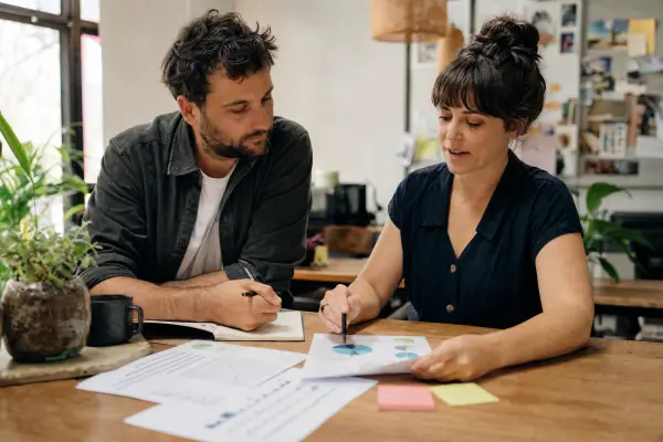 Two business owners comparing finance paperwork at a table